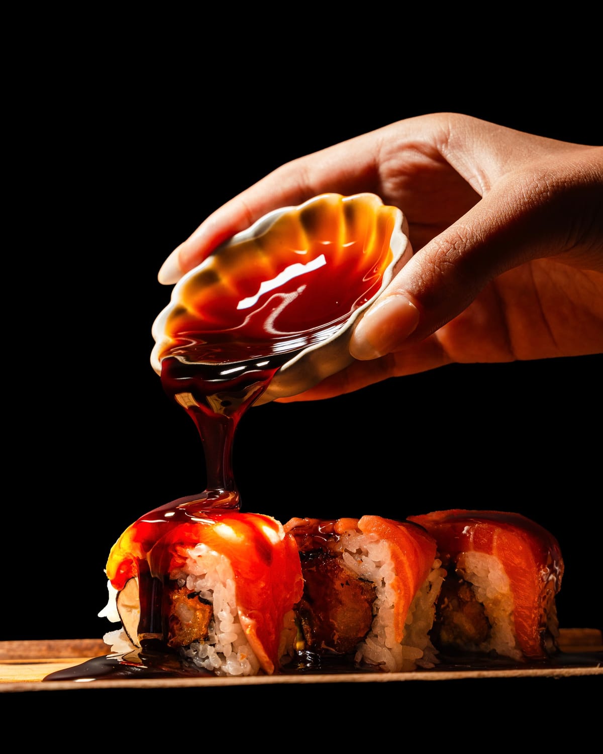 Sauce poured over a sushi roll on a dark background