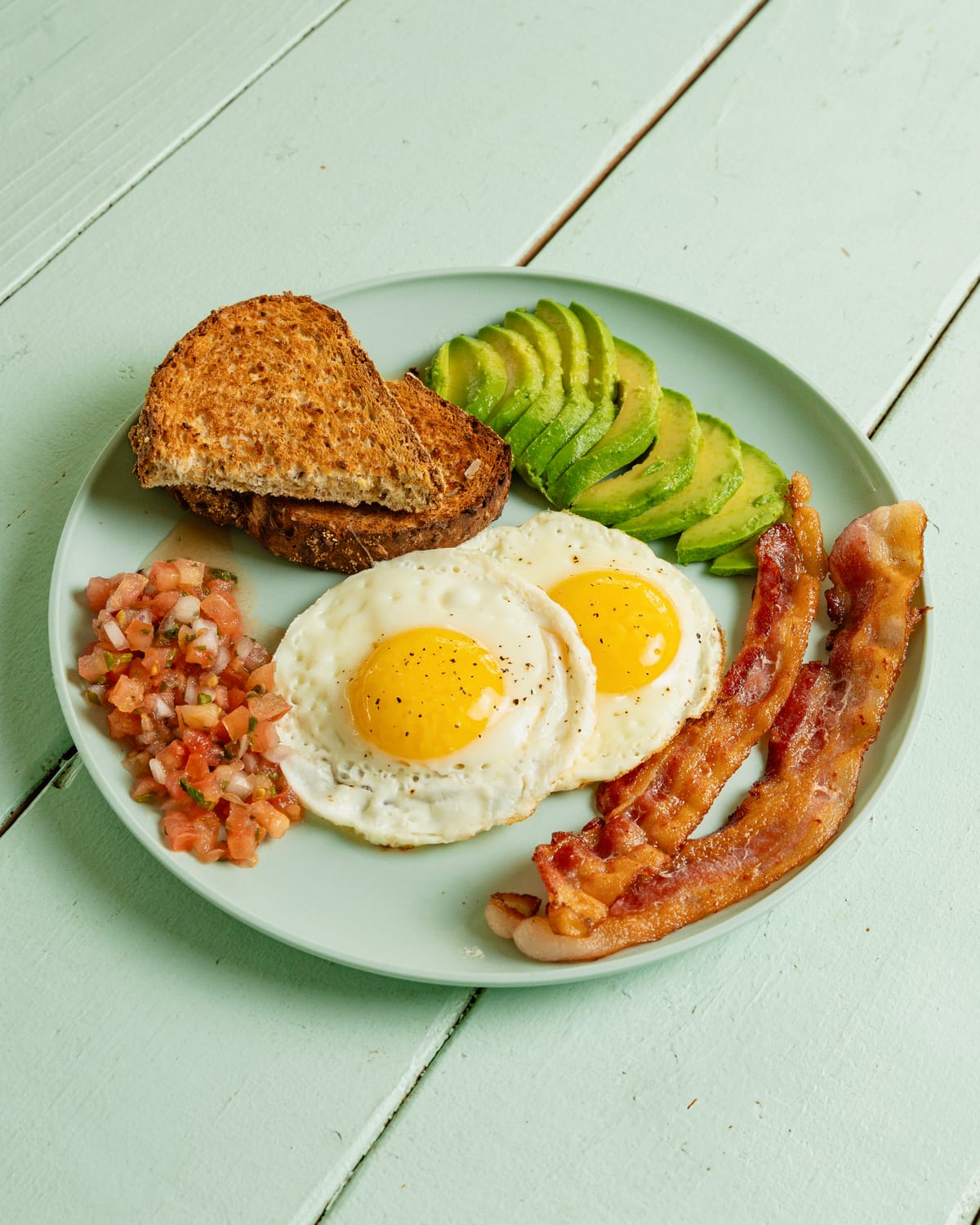 Breakfast plate with eggs, bacon and avocado toast