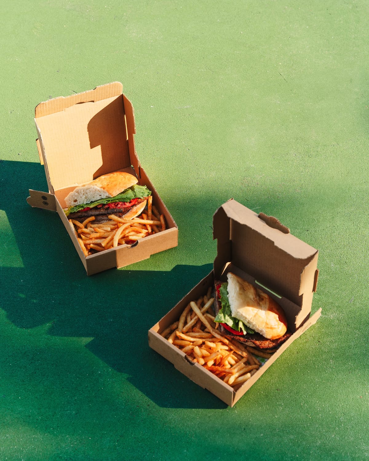 Takeaway boxes of fries on a green backdrop