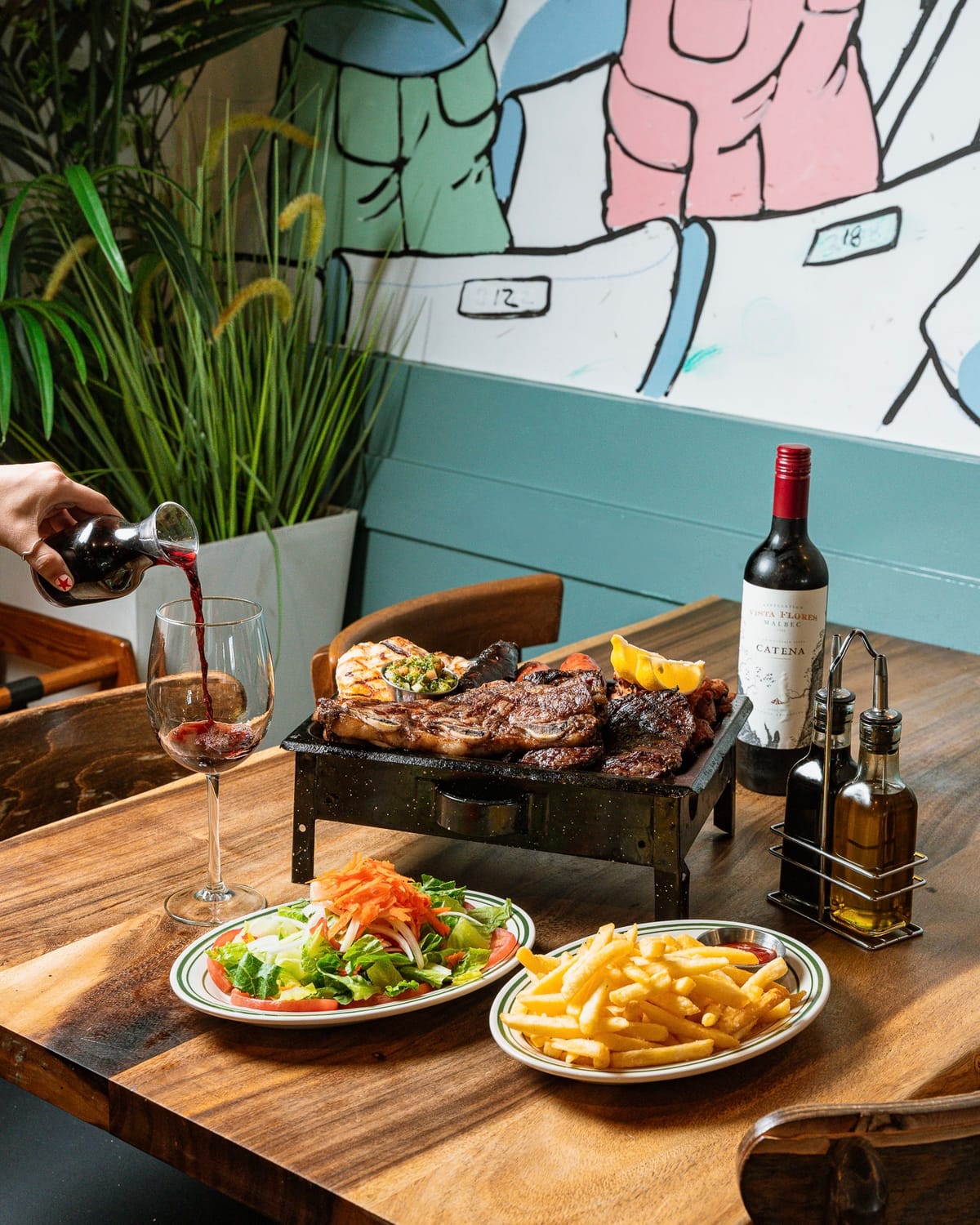 Steak and sides on a restaurant table by a mural